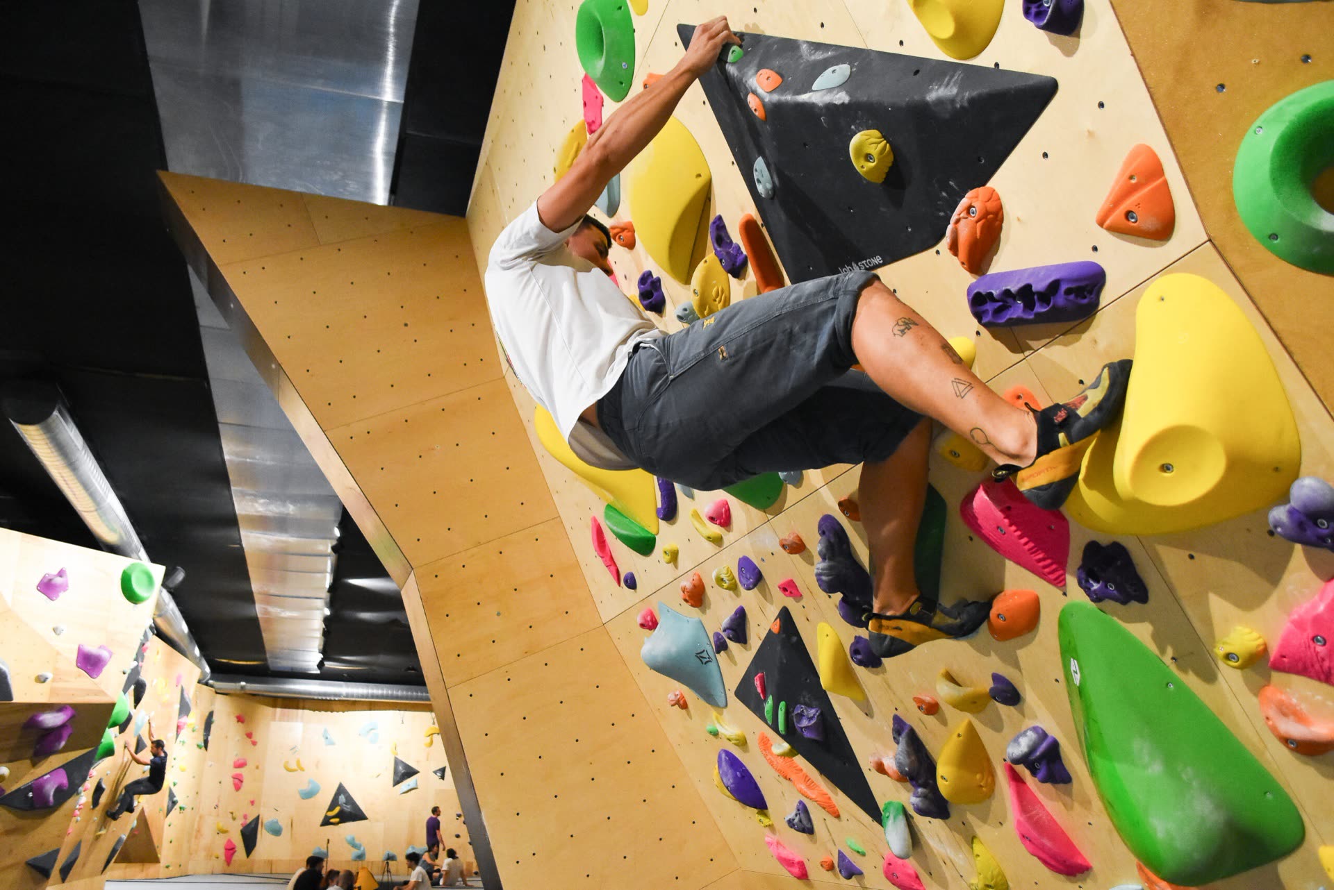 Escalador en bloque sobre pared de búlder con presas de colores en Neko Escalada